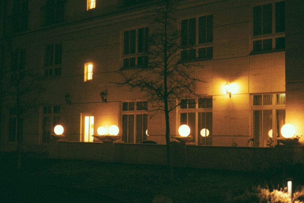a building lit up at night with a tree in front of it